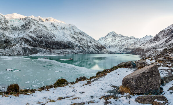 New Zealand - 10 July 2021: View of glacial Hooker Lake with floating icebergs, surrounded by snow-capped peaks of the Southern Alps in Aoraki Mount Cook National Park.