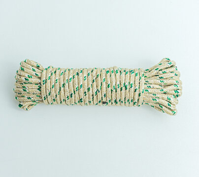 Rolled bundle of green and white twisted string rope isolated on white background
