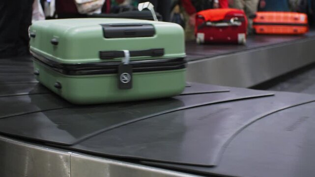 Bright green suitcase being moved around on baggage conveyor at an airport, 4k