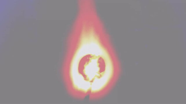 Close up view of a burning matchstick glowing bright orange and yellow in darkness.