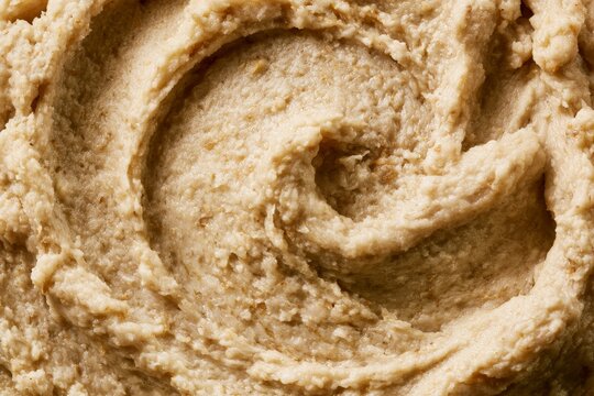 Creamy texture of hummus displayed in close-up with swirls and dips