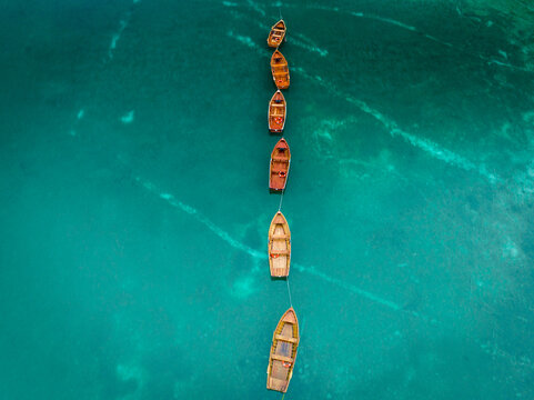 02 October 2022: View of a line of wooden boats floating on clear turquoise water.