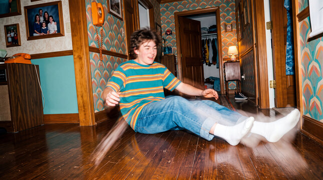 Cheerful Teenage Boy Sliding on Hardwood Floor in Retro Hallway