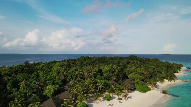 Aerial view of Meedhupparu island featuring lush tropical palm trees and resort villas surrounded by the turquoise ocean in Raa Atoll, Raa Atoll, Maldives.