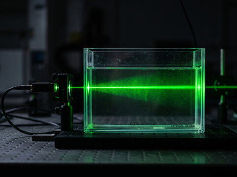 Green laser beam passing through liquid in glass cuvette Tyndall effect
