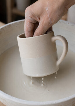 Bisque Fired Cup Being Dipped Into Ceramic Glaze
