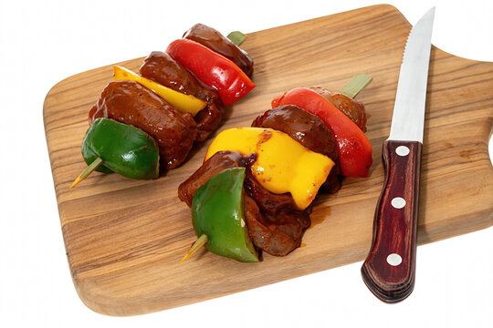 Marinated Meat Skewers with Bell Peppers on a Wooden Cutting Board with a Knife