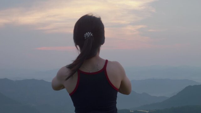 Woman practicing Urdhva Hastasana yoga pose with raised arms on a highland ridge at sunset in Mau Son, Vietnam, focusing on wellness, breathing, and mindfulness