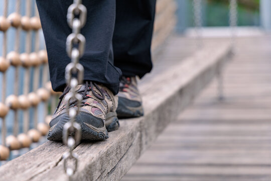 Close up of feet in hiking boots balancing on narrow wooden beam at rope climbing course, outdoor adventure and obstacle concept