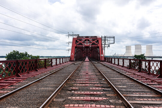 Pabna, Rajshahi Division, Bangladesh - 17 August 2025: View of the historic red steel Hardinge Bridge spanning the Padma River, with power plant cooling towers in the background.