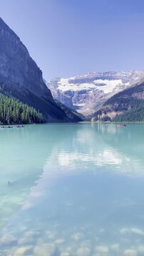 Turquoise water of Lake Louise with snow capped mountains glacier and canoes in Banff National Park Canada