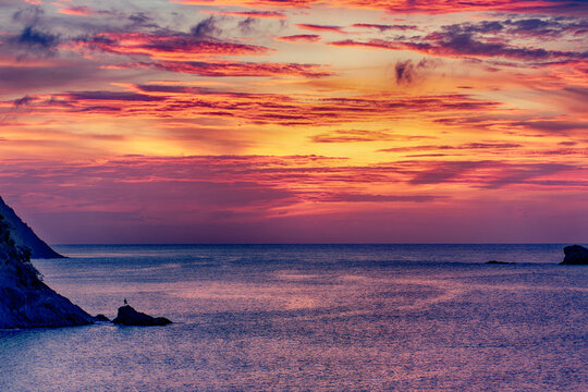 Silhouette of person on a rock in the Caribbean sea at sunset