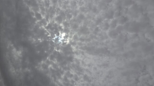 Bright sunlight breaking through gray clouds in the sky, creating a dramatic natural sky scene with soft light and cloudy atmosphere. Horizontal footage.