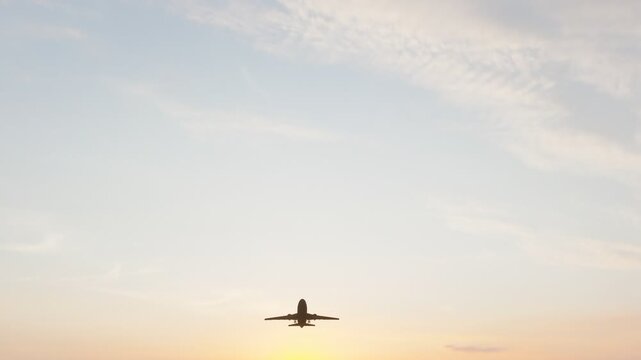 Commercial passenger airplane flying through a warm sunset sky, ideal for aviation, air travel, tourism, transportation, airline, and travel content.