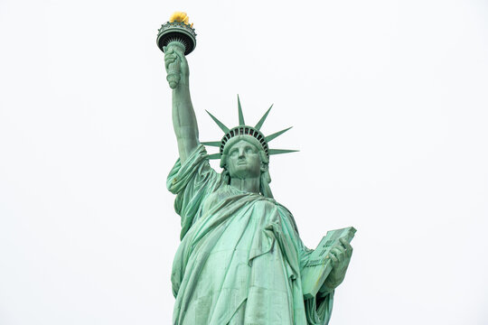 New York, New York, United States - 16 April 2023: View of the Statue of Liberty holding her torch high against a bright overcast sky.