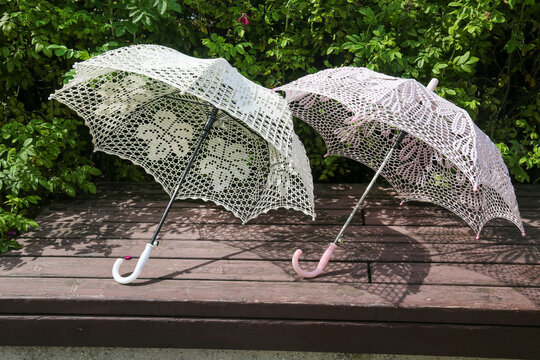 Two white lace sun umbrellas lying on a bench Design backgrounds textures interior.