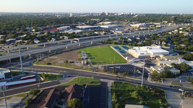 Curved arterial roadways, suburban institutional campuses border Evers Road near Loop 410 interchange. High capacity expressway spans meet neighborhood parcels in San Antonio, Texas