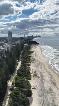 Aerial drone view of surf rolling onto Burleigh Heads beach, Gold Coast, Queensland Australia - vertical video