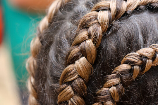 Braided hair closeup showing intricate brown plait detail, textured strands, and stylish youthful hairstyle viewed from above in natural light