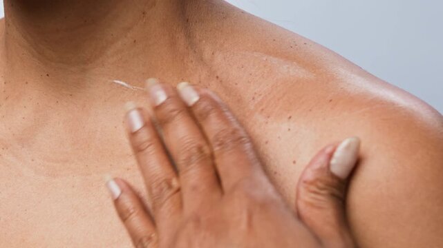 Cropped shot of unrecognizable woman applying moisturizing cream to her collarbone on studio background. Footage is perfect for skincare brand advertising