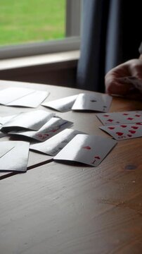 The hands lay out the playing cards on the table. A close-up of the hands of a fortune-teller, the cards are laid out in a row on the surface, the home environment.