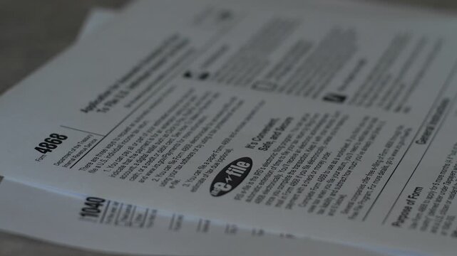 Close-up shot of US tax Form 1040 and Form 4868 with a pen placed on top of the documents. Official IRS paper forms prepared for income tax filing 