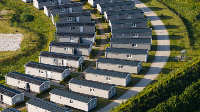 Aerial view of a modern holiday park with rows of grey mobile homes featuring solar panels on their roofs, situated in a green landscape in Venlo, Limburg, Netherlands.