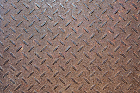 Rusty diamond plate metal surface with repeating raised tread pattern, weathered corrosion and rough industrial texture. Seamless-style background suitable for industrial, construction and design proj