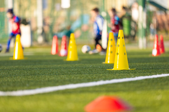 Soccer Training Camp For Children. Bright Yellow and Red Agility Cones Set Up on Green Turf Pitch for Youth Soccer Practice and Skill Drills