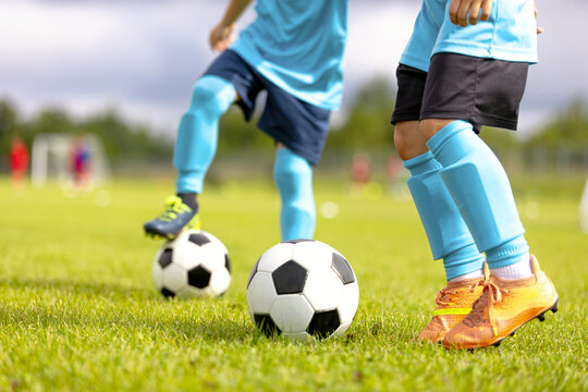 Close-Up of Junior Soccer Players in Blue Kits Practicing Ball Control and Dribbling Drills on Green Grass Pitch