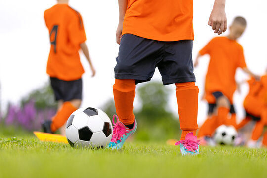Junior Soccer Team in Orange Uniforms Dribbling and Passing Balls During Group Practice Session on Grass Field