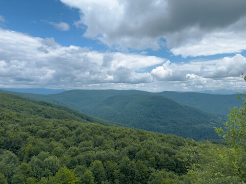 Scenic summer landscape of endless forested rolling hills Carpathian mountain slopes under cloudy blue sky in summer