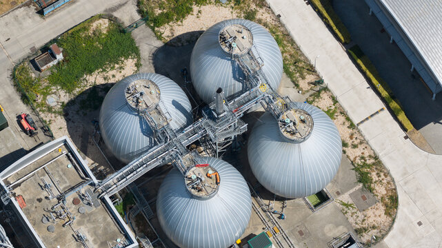Aerial view of industrial spherical digester tanks connected by metal walkways at a wastewater treatment facility in Reading, England, United Kingdom.