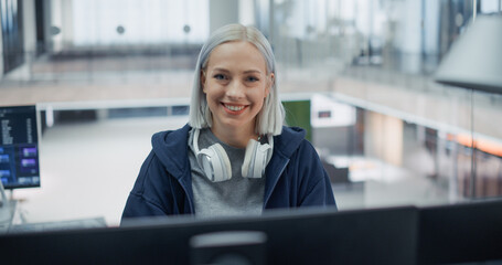 Portrait of a Cheerful Caucasian Female Software Engineer With Platinum Hair and White Headphones...