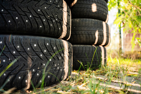 View of a stack of winter tires with metal studs resting on the grass in Riga, Latvia.