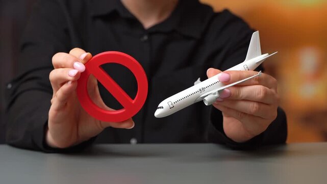 Woman holds a prohibitory sign near an airplane. Sanctions. Refusal of aircraft insurance, breaking leasing agreements. Closing air routes. Flight cancellation. Failure safety tests. Restrictions