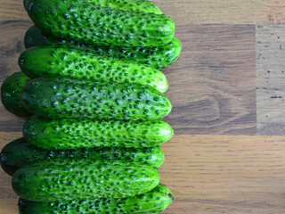organic Cucumbers Stacked on Wooden Surface, copy space, high angle view © Irina