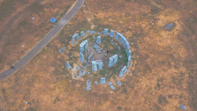 Aerial view of Stonehenge, a prehistoric monument with massive standing stones in a circle, surrounded by grassy fields and a walking path in Salisbury, England, United Kingdom.
