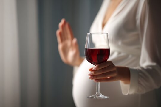 Pregnant woman holding a glass of red wine with a gentle hand gesture in a soft light setting showcasing the concept of moderation and health awareness during pregnancy. Generative AI