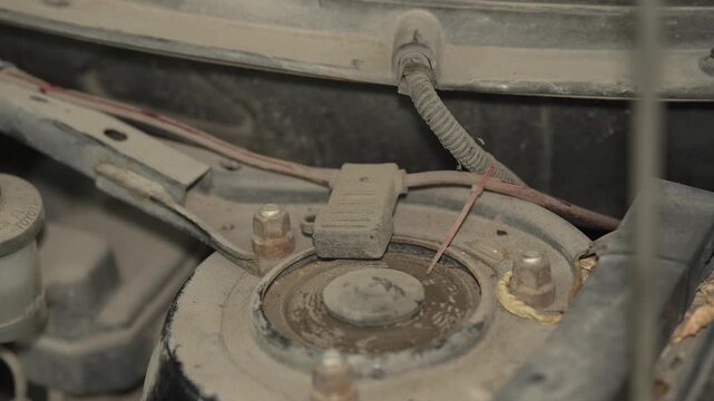 A close up of a dusty front shock absorber strut mount.