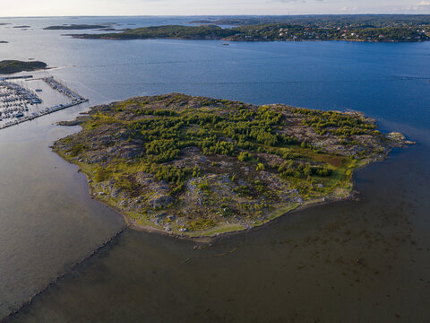 Aerial view of Sando island in the archipelago, featuring rocky terrain, green vegetation, and surrounding blue sea waters near Vallda, Hallands lan, Sweden.