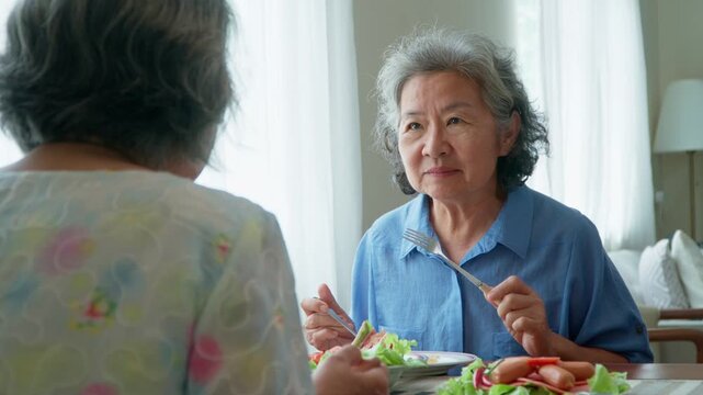 Group of Joyful senior women with gray hair having breakfast together at home. Elderly retired woman friends enjoying a plate of food, exuding warmth and contentment. Enjoy the retirement life concept