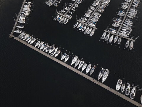Aerial view of Sando marina with rows of sailboats docked in calm dark water, Vallda, Hallands lan, Sweden.