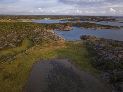 Aerial view of Sando featuring rocky coastal terrain, lush greenery, and calm inlets along the shoreline in Vallda, Hallands lan, Sweden.