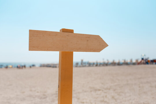 Wooden arrow on the beach. Empty sign.