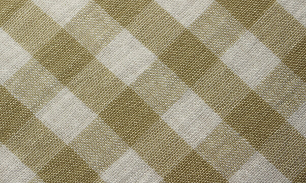 Close up of wrinkled diagonal ocher gingham cloth background. Texture of crumpled gold and white plaid fabric. 