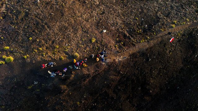 Aerial view of hikers trekking along a rocky path on the volcanic slopes of Mount Agung in Rendang, Bali, Indonesia.