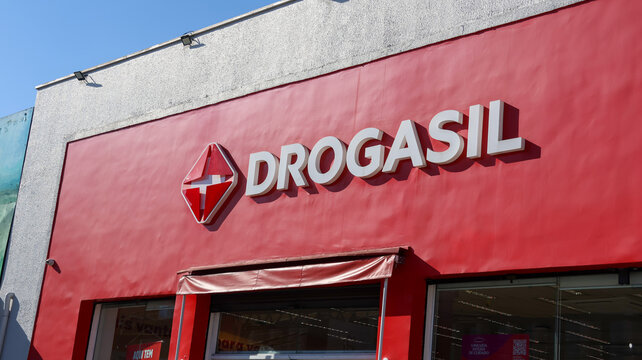 Fachada da Drogasil com grande logotipo vermelho e branco acima da entrada da farm&aacute;cia, destacando a identidade visual da rede varejista em &aacute;rea urbana local. Mogi das Cruzes SP 18 agosto 2026