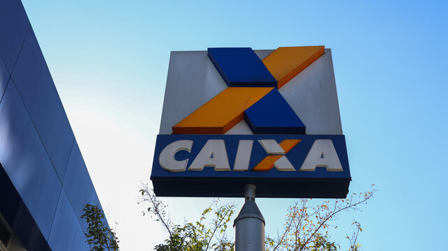 Placa externa da Caixa Econ&ocirc;mica Federal com logotipo da institui&ccedil;&atilde;o contra o c&eacute;u azul, registro de servi&ccedil;o banc&aacute;rio e urbano em Mogi das Cruzes, S&atilde;o Paulo, Brasil, em 22 de agosto de 2026