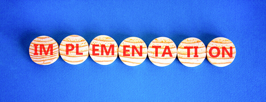 Implementation word symbol. Concept word Implementation on beautiful wooden circles. Beautiful blue background. Business implementation word concept. Copy space.